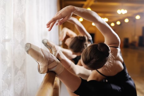 Three dancers performing on a ballet barre