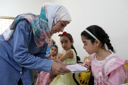 Ghanem shows a young girl, one of her pupils, a piece of paper.