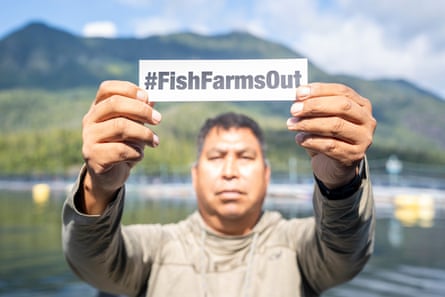 Skookum John 举着一块牌子,上面写着“#FishFarmOut”