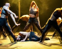 Harvey Burke-Hamilton lies curled on stage as dancers crouch and lean around him