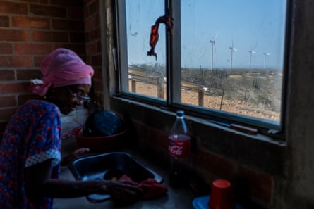 A woman at a kitchen sink with a view of turbines outside the window