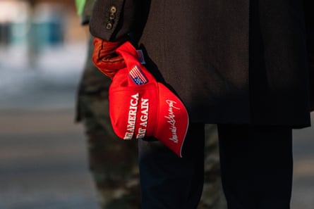 Hand at person’s side holds red cap