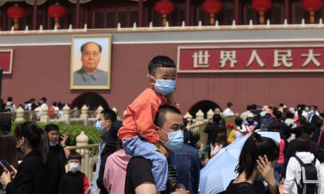 A man and child visit Tiananmen Gate near a portrait of Mao Zedong in Beijing