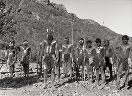 Aboriginal men, some holding spears, in rocky country