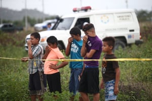 Children cover their noses near the body of a man who was killed in San Pedro Sula