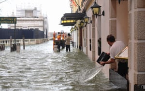 A man empties a bucket of water on a flooded street during a high-water (Acqua Alta) alert in Venice.