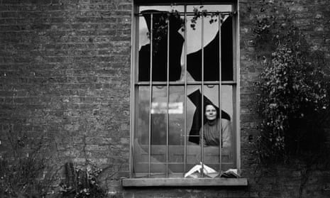 A woman peers through a shattered window at Holloway prison