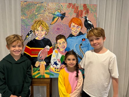 Two boys, with a girl in between, stand in front of a painting of them