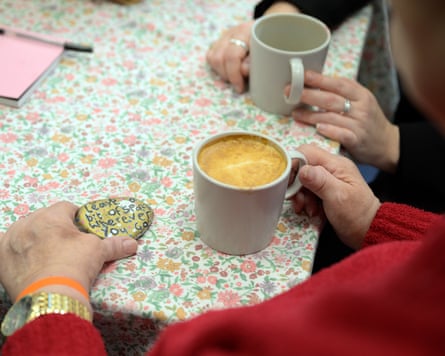Closeup of an anonymous woman holding a cup of coffee and a stone decorated with the words 'Leave a bit of sparkle wherever you go'