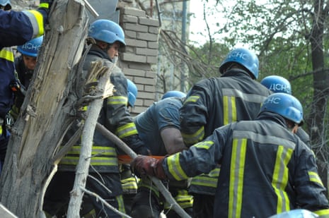 Rescuers carry an injured local resident at the site of a residential building heavily damaged by a Russian missile strike.
