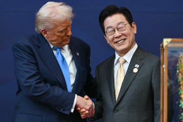 Donald Trump looks towards a smiling Lee Jae Myung as they shake hands