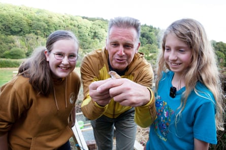 Two teenage girls and a man pose with a small mouse