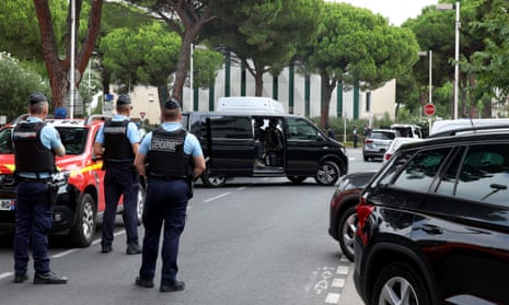 Police officers standing on a blocked-off road with a building in the distance behind