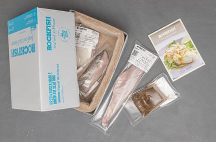 A cardboard box with portions of fish in plastic and a recipe leaflet
