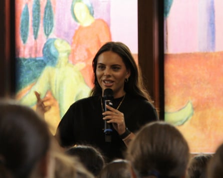 She is holding a microphone and speaking to a group of children