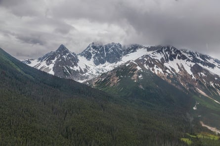 Distant view of snowy mountains peaks under cloudy sky.