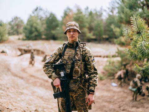 لونتیک ایستاده و با اسلحهای در دست به دوربین نگاه میکند