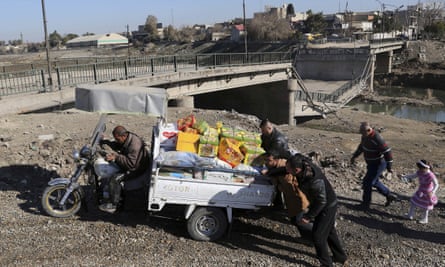 Men push a motorcycle cart loaded with possessions next to a collapsed river bridge in Mosul