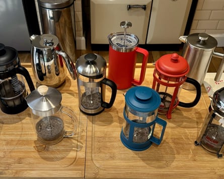 Nine cafetières on a wooden kitchen counter.