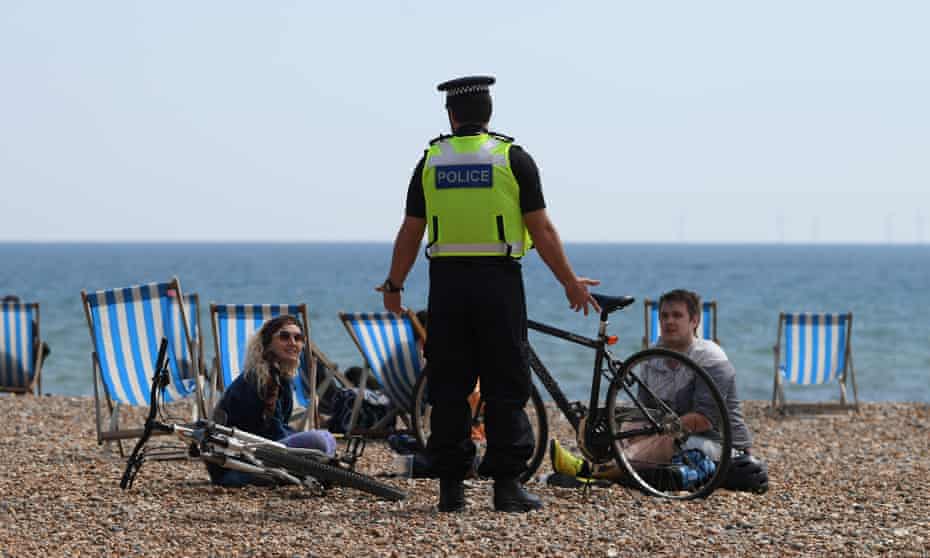 A police officer talking to people on the beach in Brighton, May 2020