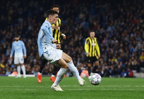 Phil Foden, in light blue, kicks the ball towards goal to score during a Champions League match