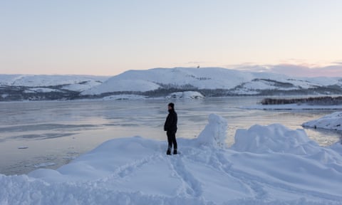 Man stands by fjord with snow everywhere