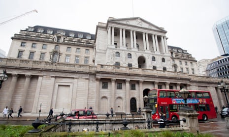 A red bus drives past the Bank of England