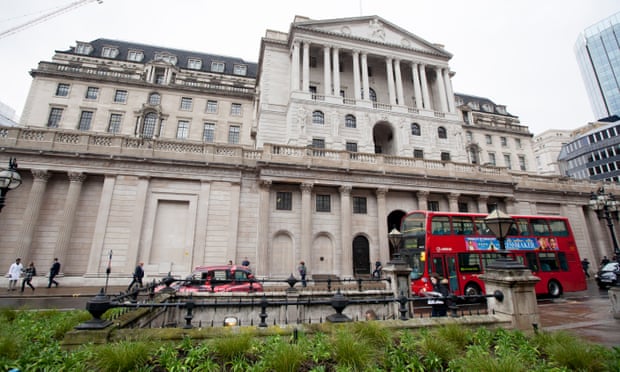 A red bus drives past the Bank of England on Threadneedle Street