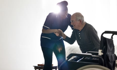 Female nurse helping senior man get up from bed at home