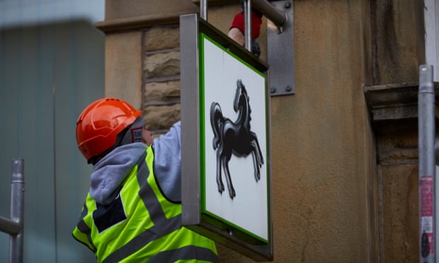 A workman dismantles a Lloyds sign from a closed branch in Hebden Bridge, Yorkshire.