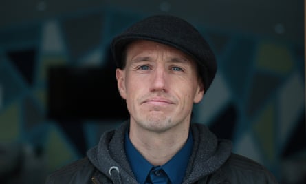 Man with cap on looks into camera
