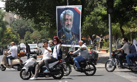 Motorcyclists ride past a poster of the Iranian presidential candidate Saeed Jalili.