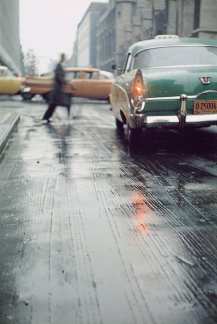 Rainy New York street scene, 1950s cars, blurred pedestrian