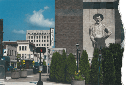 A mural of a man on the side of a brick building in a downtown city area