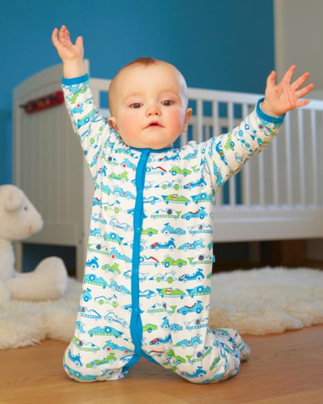 Toddler playing on floor wearing babygro with cars on it