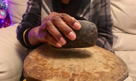 A woman holds a stone used for breast-ironing.