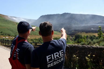 Firefighters point towards the smoke from a moorland fire near the Dovestone reservoir in Greater Manchester.