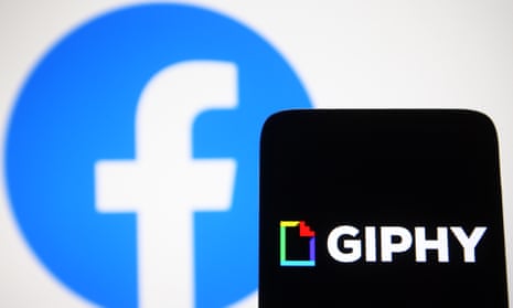 A Giphy logo is seen on a smartphone screen with a Facebook logo in the background