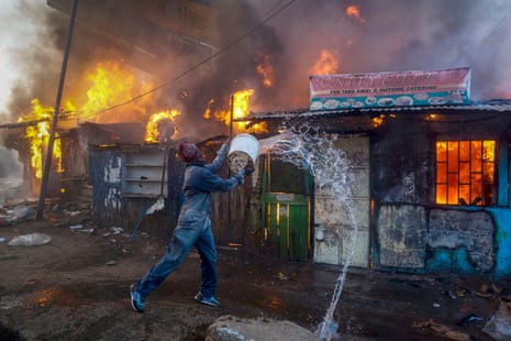 A man battles a fire at a shop in Kawangware slum, Nairobi, during post-election violence, October 2017. 