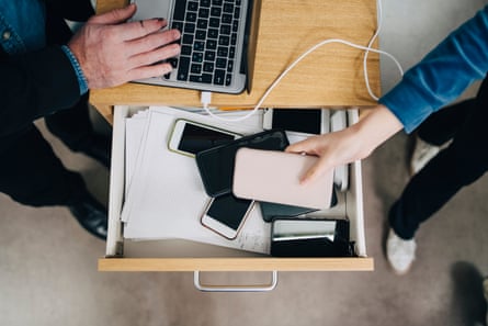 High angle view of female student putting a phone in a drawer in school.