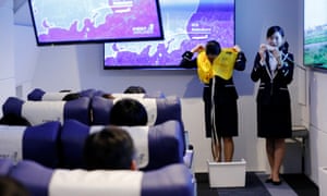 Staff dressed as flight attendants perform a safety demonstration.