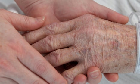 A nurse holds the hand of an elderly patient.