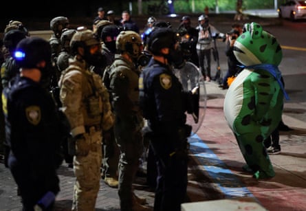a person in a frog costume in front of police