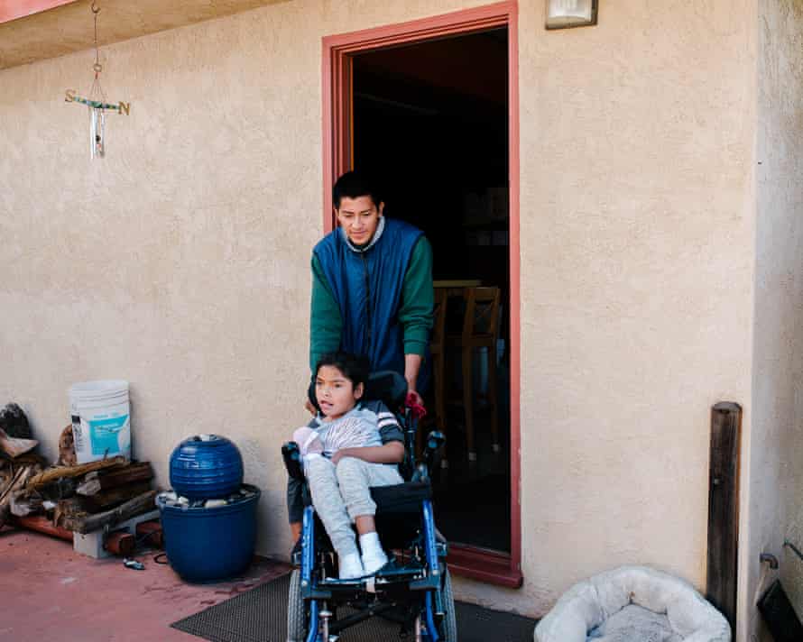 Juan Antonio wheels his daughter Lesly into the backyard of their host’s home so they can eat in the garden together.