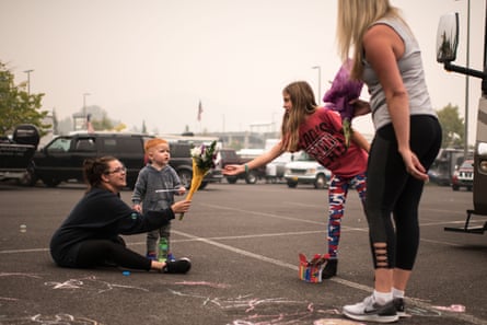 Rebecca Manley and her son, James, accept a bouquet from volunteers handing out flowers at an evacuation site in the parking lot of the Clackamas Town Center on 11 September 2020.