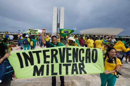 Protesters hold a sign that reads “intervencao militar”, meaning military intervention.