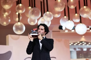 A man dressed in black tie kisses a statuette of silver lion on stage