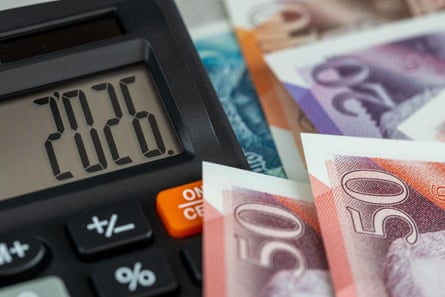 A calculator shows the 2026 digits next to a pile of high denomination sterling banknotes