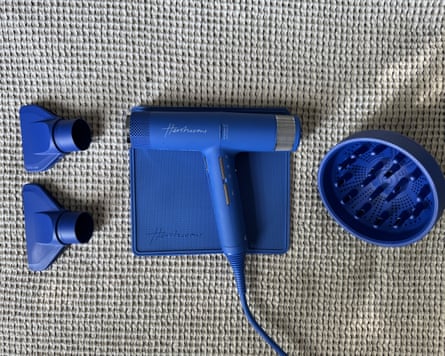 Hershesons’ The Great hairdryer on its heat proof mat and two nozzle heads and a diffuser attachment. The dryer and parts are all bright blue.