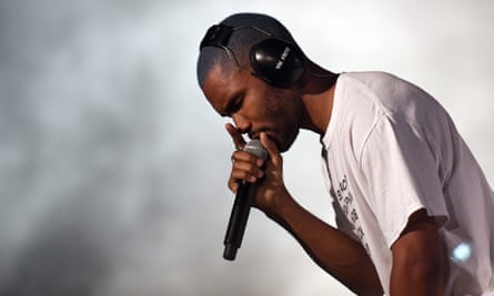 Frank Ocean sings into a microphone against a backdrop of fog.